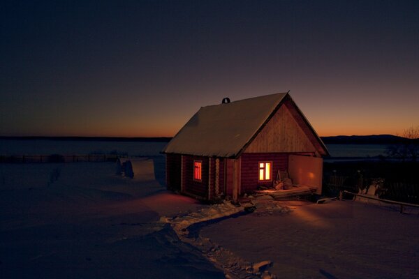 Casa en un campo de invierno por la noche