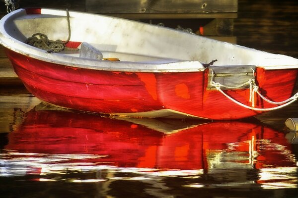 Rotes Boot am Steg und Reflexion im Wasser