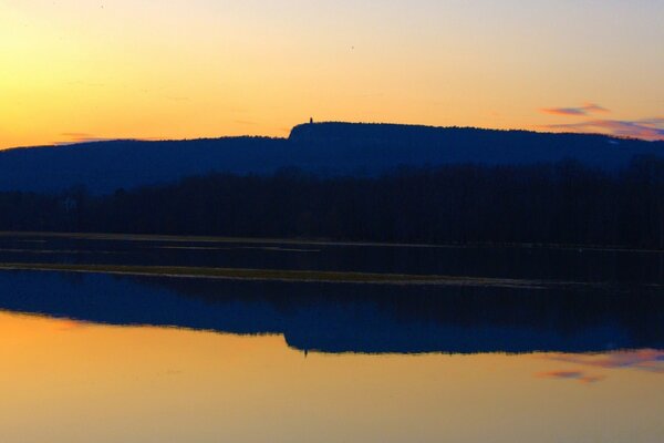 Blick vom Ufer auf den lila- orangefarbenen Sonnenuntergang