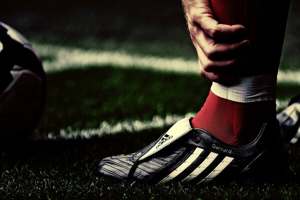 A football player adjusts his sneakers on the field