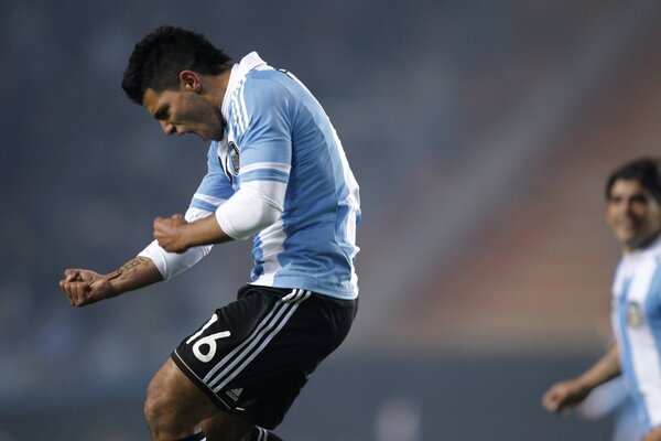 A football player in a blue uniform sincerely rejoices at the incident at the match