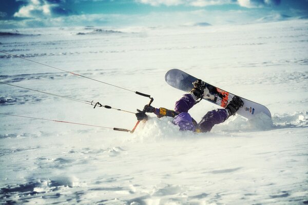 A man fell into the snow on a snowboard