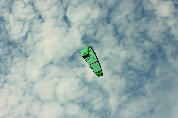 Parapente verde en el cielo nublado