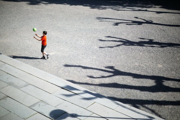 In the sidewalk, a boy plays a ball, they said play on the flat