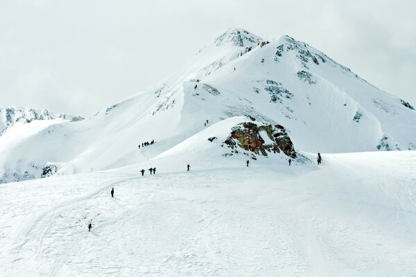 Skiers descend from a snowy peak