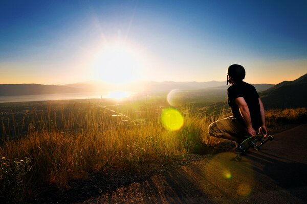 A man sits with a skate at sunset