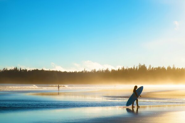 A girl with a surfboard on the shore