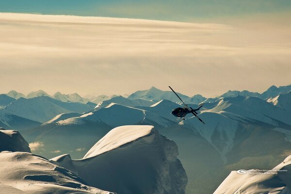 Hubschrauber fliegt zwischen verschneiten Berggipfeln