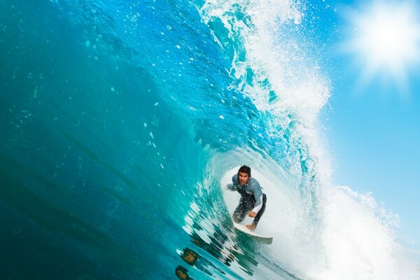 Surfeur roule sous la vague sur une planche