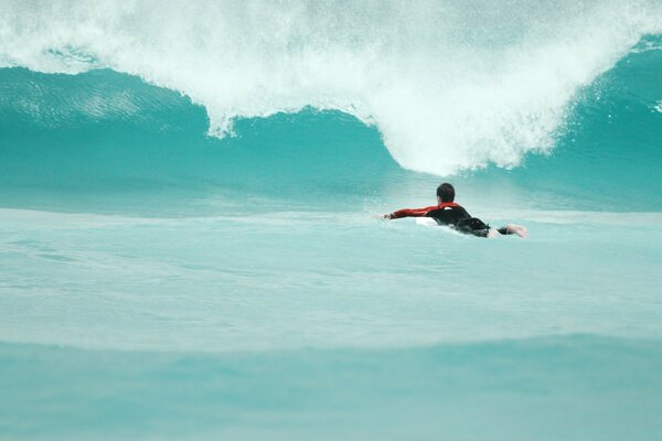 A man swims through the water to the wave