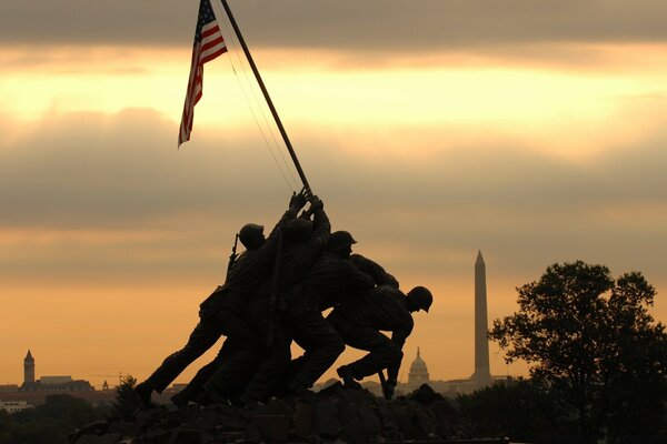 Silhouette de personnes avec drapeau américain au coucher du soleil