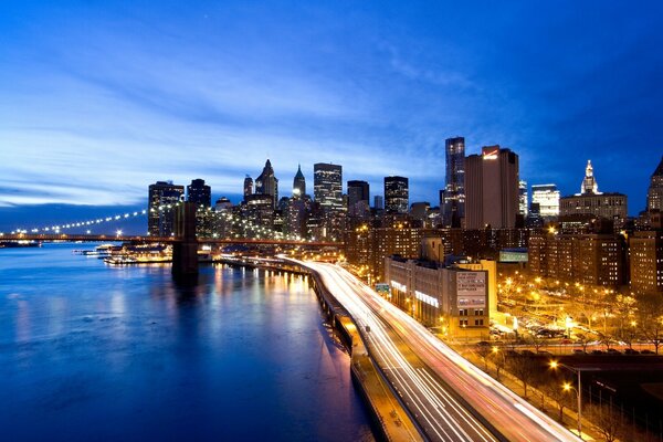 A city on the seashore with a lighted bridge