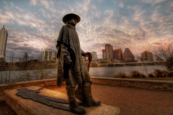 A statue of a man against a beautiful sky