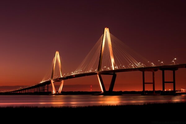 Puente nocturno sobre el agua iluminado por luces