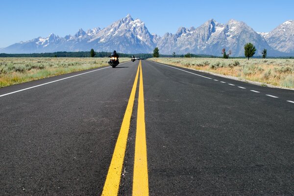 Route partant au loin vers les sommets des montagnes