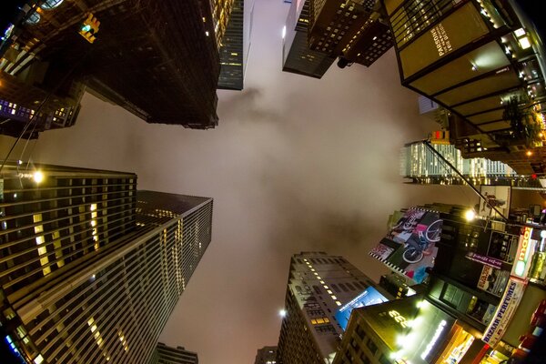 In the center is the night sky in fog bordered by skyscrapers in lights