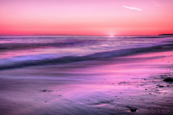 Playa de arena y puesta de sol rosa