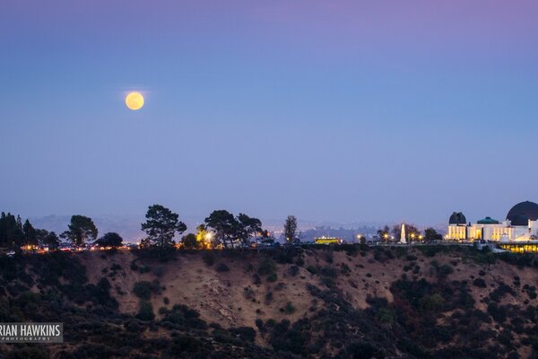 The moon in the sky against the background of the evening city