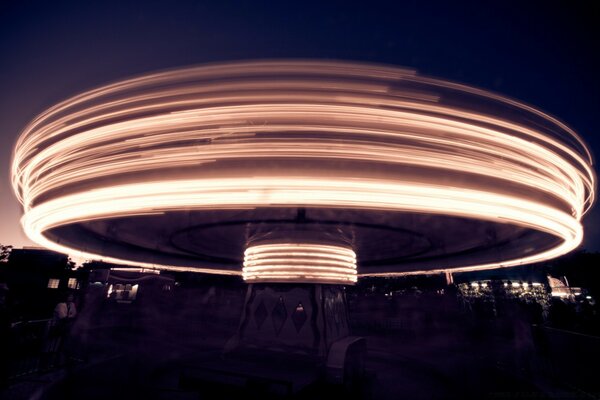 A round large building on one support against the background of the night city