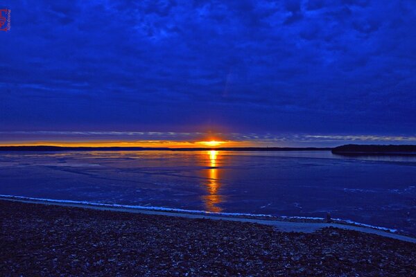 Nubes azules saturadas que cubren la puesta de sol sobre el lago