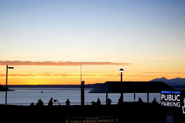 Tramonto sul molo con sagome di persone