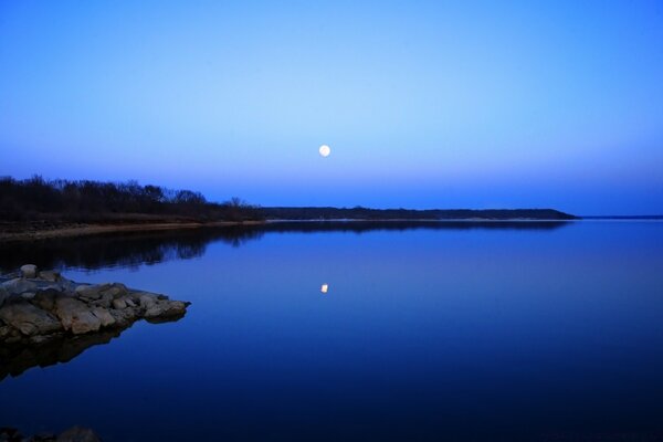 La luna si riflette in un lago calmo