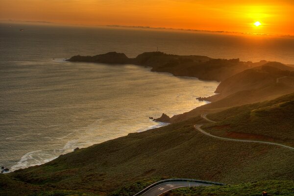 Puesta de sol en el mar con vistas a las montañas y las nubes