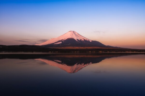 A mountain with a snowy peak on the background of water