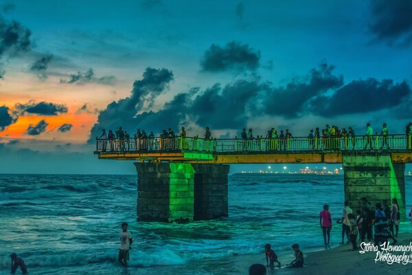 Die Leute auf der Brücke schauen den Sonnenuntergang an