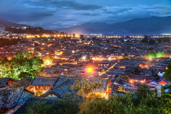 Una piccola città asiatica vicino alle montagne è illuminata da luci notturne