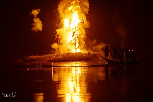 Nächtliches Feuer in der Nähe des Flussufers