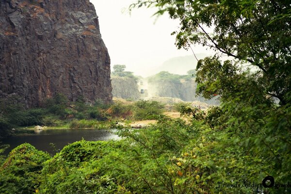 Paisagem verde com uma rocha sobre a água