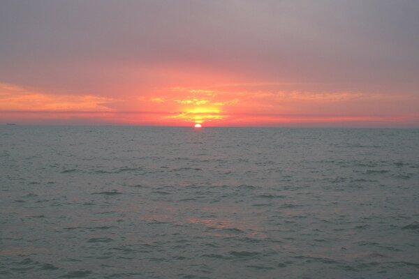 Закатное солнце садится в серое море