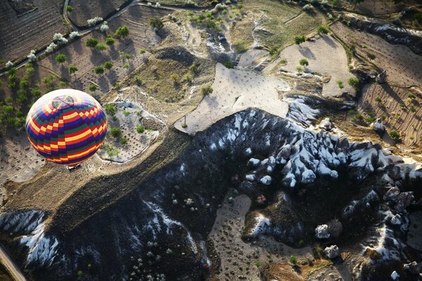 A bright balloon is flying over the mountains