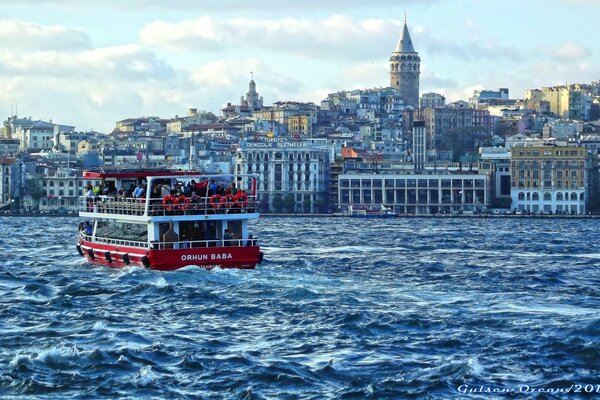 Şehrin arka planına karşı su üzerinde yürüyen bir yat