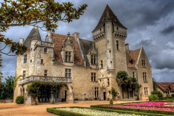 Castillo gótico contra el cielo y los macizos de flores