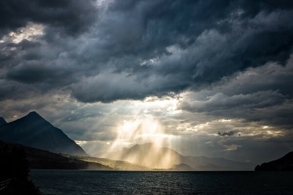 Berge und Seen, die von der Sonne beleuchtet werden, die aus den Wolken späht