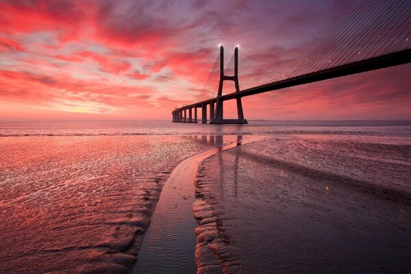 Puesta de sol roja del océano con el puente