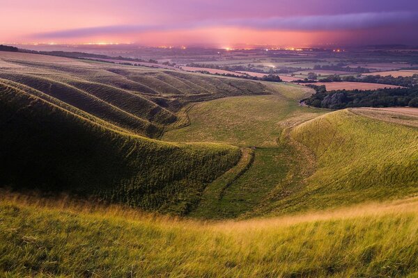 Sunset landscape on the background of green fields and mountains