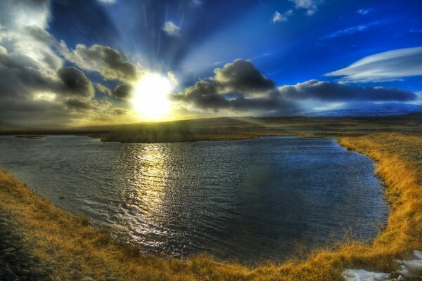 El sol se abre paso a través de las nubes sobre el lago