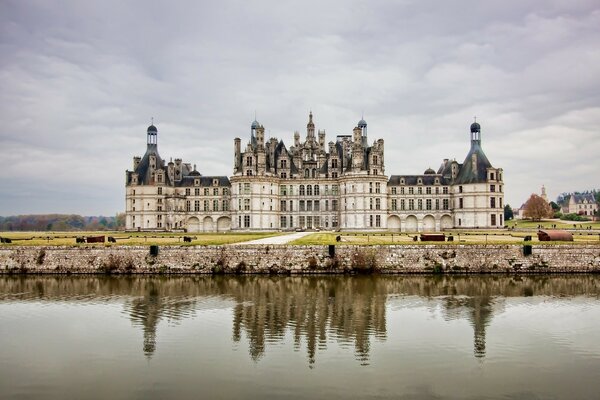 A castle on the shore of a lake with a reflection in it