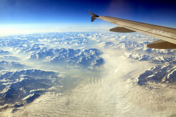 Unter dem Flügel des Flugzeugs werden die Berge weiß (anscheinend die Alpen), weil er den Weg nach Europa anstrebte