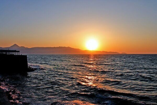 Schöner Sonnenuntergang am Meer. Felsen am Horizont