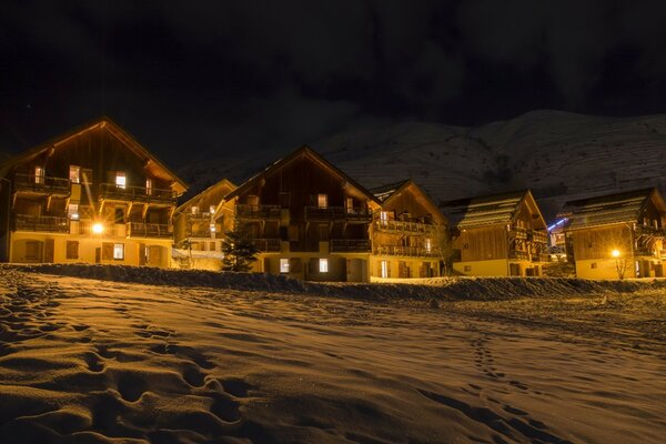 Vista nocturna de invierno de pequeñas casas europeas en las montañas