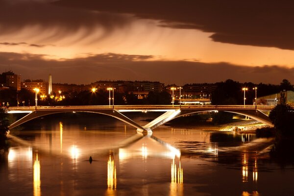 Hermosa vista de la ciudad Europea. Puente iluminado sobre el río