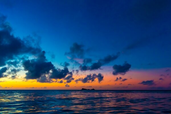 El sol en las nubes se pone sobre el mar