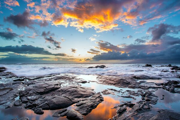 Surf rolls on the rocky shore during sunset