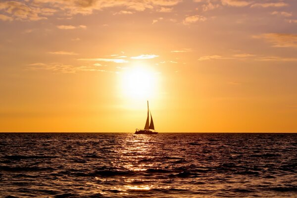 A lone sail at sunset rushing to the horizon