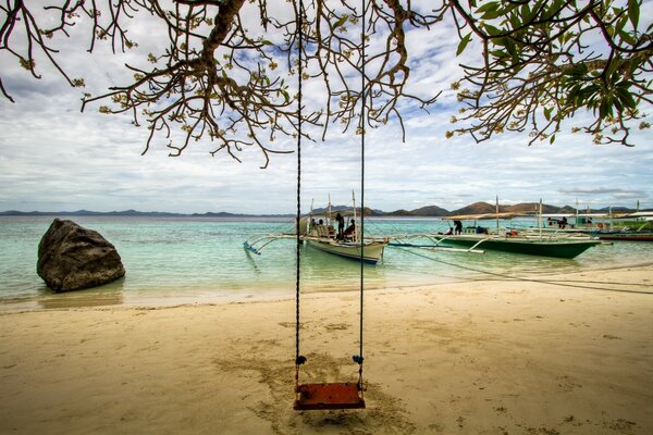 Hanging swing on the beach by the water