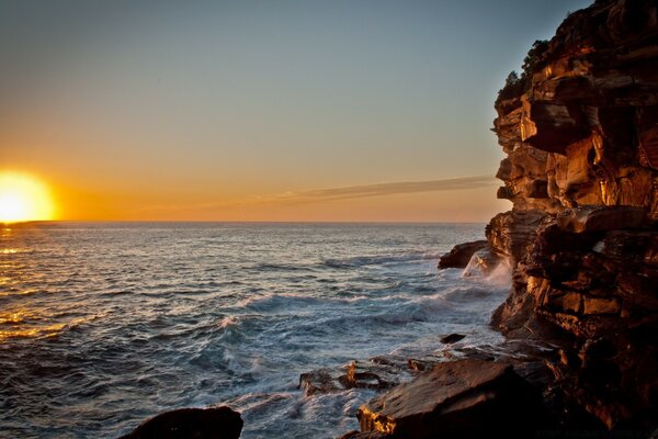 Costa rochosa do mar contra o pôr do sol